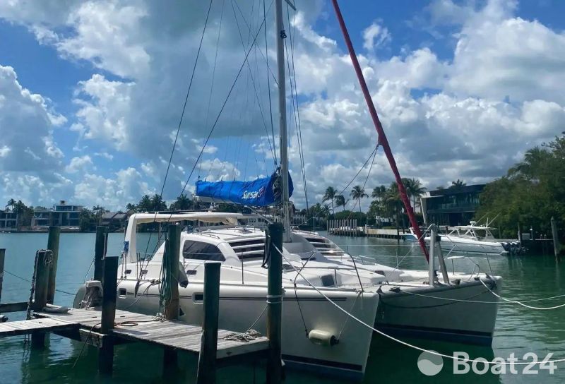 2003 Leopard 38 catamaran docked in a sunny marina with blue skies.