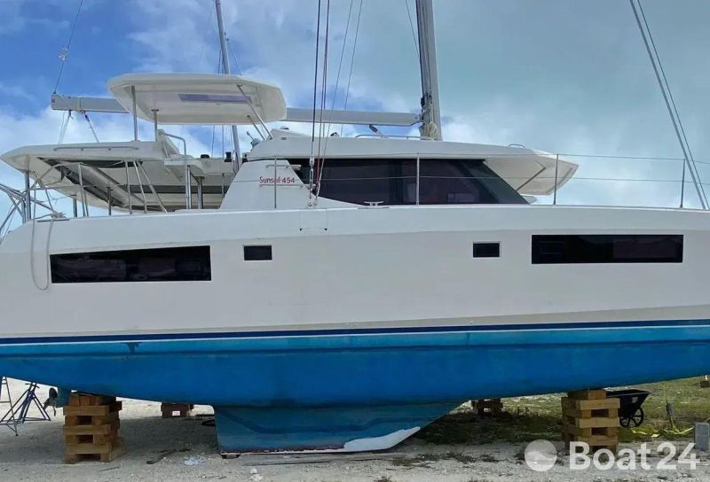 2020 Leopard 45 catamaran on land, white and blue hull, cloudy sky background.