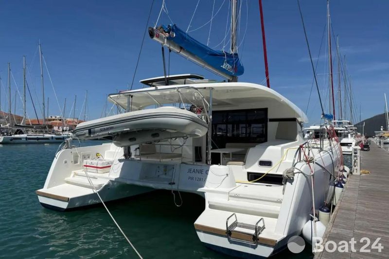 2020 Lagoon 42 catamaran docked at marina, featuring a dinghy and clear blue sky.