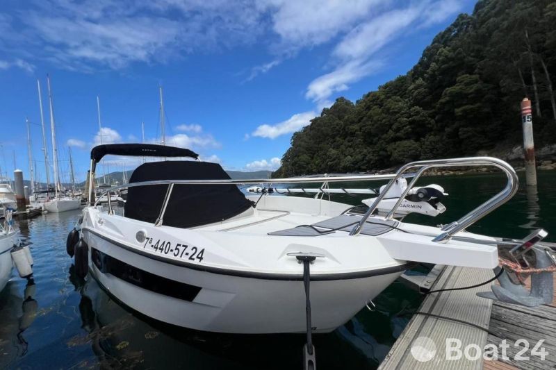 2024 Karnic SL 702 boat docked at marina, surrounded by lush greenery and clear skies.