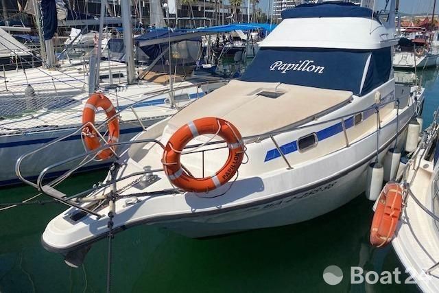 Astinor 1000 boat from 1998 docked in marina with lifebuoys.