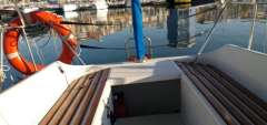 Sailboat cockpit with wooden benches, life preserver, and marina view; Feeling 286, 1988 model.