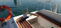 Sailboat cockpit with wooden seats, life preserver, and calm water reflection. Feeling 286, 1988 mod