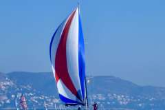 Sailboat with colorful spinnaker, Grand Soleil 40, 2005, sailing near coastal hills.