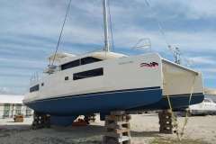 2020 Leopard 45 catamaran on blocks, white hull, blue accents, clear sky background.