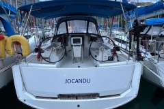 2018 Jeanneau Sun Odyssey 389 sailboat docked, featuring dual steering wheels and blue canopy.