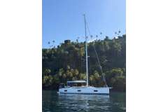 2022 Nautor Swan 48 yacht at anchor near lush tropical coastline.