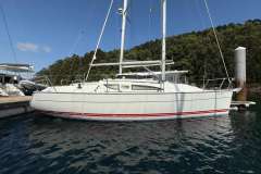 2002 Jeanneau Sun Fast 32i sailboat docked in a marina, surrounded by lush greenery.