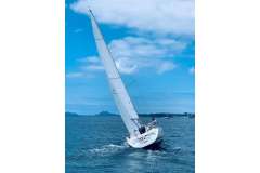Sailing Jeanneau Sun Fast 32i, 2002 model, on open sea under clear blue sky.