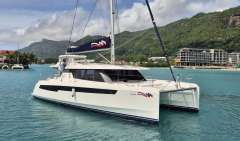 2020 Leopard 50 catamaran sailing in tropical waters with lush green mountains in the background.