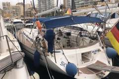 Sailboat Bavaria 44, 2002 model, docked in a marina with cityscape background.