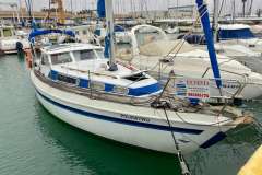 Sailboat Mascot 28, 1986 model, docked at marina, for sale sign visible.