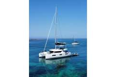 2022 Lagoon 46 catamaran anchored in clear blue waters, under a sunny sky.