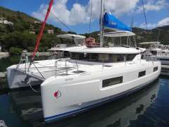 2020 Lagoon 46 catamaran docked in a scenic marina with lush hills and blue skies.