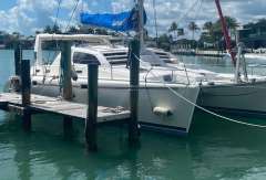 2003 Leopard 38 catamaran docked in a sunny marina with palm trees.