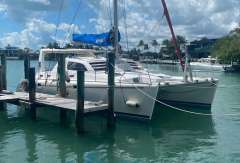 2003 Leopard 38 catamaran docked in a sunny marina with palm trees.
