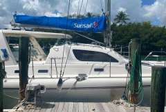 2003 Leopard 38 catamaran docked, featuring a blue Sunsail cover and lush tropical backdrop.