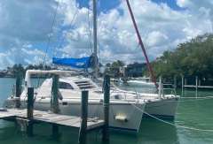 2003 Leopard 38 catamaran docked in a serene marina under a partly cloudy sky.