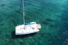Aerial view of 2008 Leopard 38 catamaran sailing on clear turquoise waters.