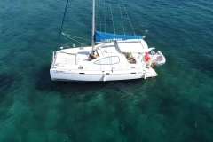Aerial view of 2008 Leopard 38 catamaran sailing on clear turquoise waters.