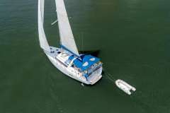 Aerial view of 2013 Beneteau Oceanis 41 sailboat with dinghy on calm water.
