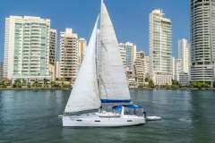 2013 Beneteau Oceanis 41 sailboat cruising near urban skyline on a sunny day.