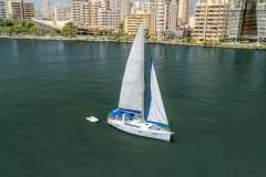 Sailboat Beneteau Oceanis 41, 2013 model, cruising near urban waterfront buildings.