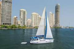 Sailboat Beneteau Oceanis 41, 2013 model, cruising near urban skyline on a sunny day.