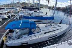 2024 Beneteau Oceanis 461 sailboat docked in a marina with blue canopy.