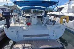2024 Beneteau Oceanis 461 yacht with dual steering wheels and blue canopy at marina.