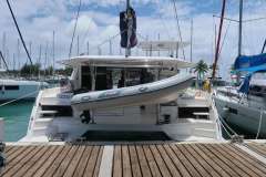 2019 Leopard 40 catamaran docked with dinghy, surrounded by sailboats under a partly cloudy sky.