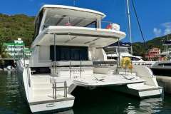 2022 Leopard 53 Powercat yacht docked in a marina, surrounded by lush greenery.