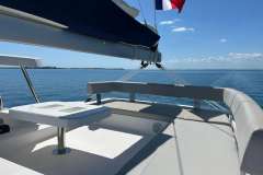 2022 Leopard 42 catamaran deck with seating, table, and ocean view under clear blue sky.