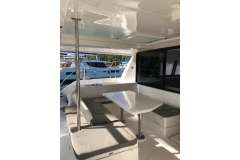 Interior of 2020 Leopard 40 catamaran with seating and table, docked at marina.