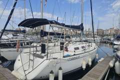 2008 Dufour 325 Grand Large sailboat docked in a marina, surrounded by other boats.