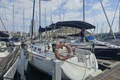 Sailboat Dufour 325 Grand Large 2008 docked in a marina with cityscape background.