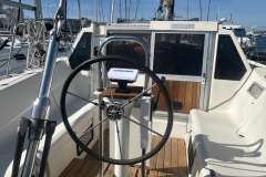Cockpit of 1983 Jeanneau Espace 1000 sailboat with steering wheel and navigation equipment.