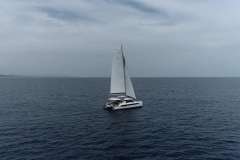 Sailing catamaran Leopard 42, 2021 model, cruising on open sea under cloudy sky.