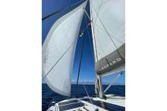 Sailing on a 2021 Leopard 42 catamaran with full sails against a clear blue sky.
