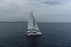 Sailing catamaran Leopard 42, 2021 model, cruising on open sea under cloudy skies.