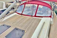 2019 Hanse 508 yacht with teak deck and red canopy in marina.