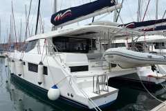 2020 Leopard 45 catamaran docked with dinghy, featuring sleek design and spacious deck.