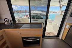Interior view of 2020 Lagoon 42 catamaran kitchen with marina backdrop.