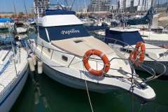 Astinor 1000 boat from 1998 named "Papillon" docked in a marina.